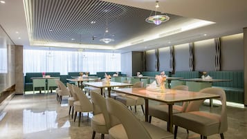 A modern restaurant interior with a central dining area, booths, and a bar.
