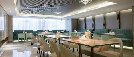 A modern restaurant interior with a central dining area, booths, and a bar.
