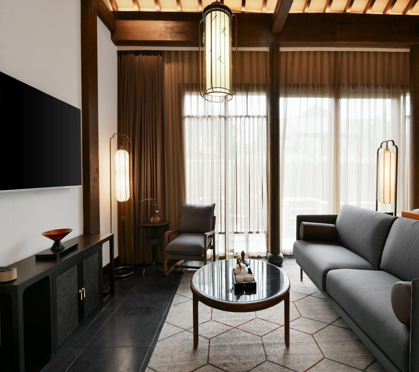 A modern living room with a sofa, a coffee table, a TV, and a lamp.