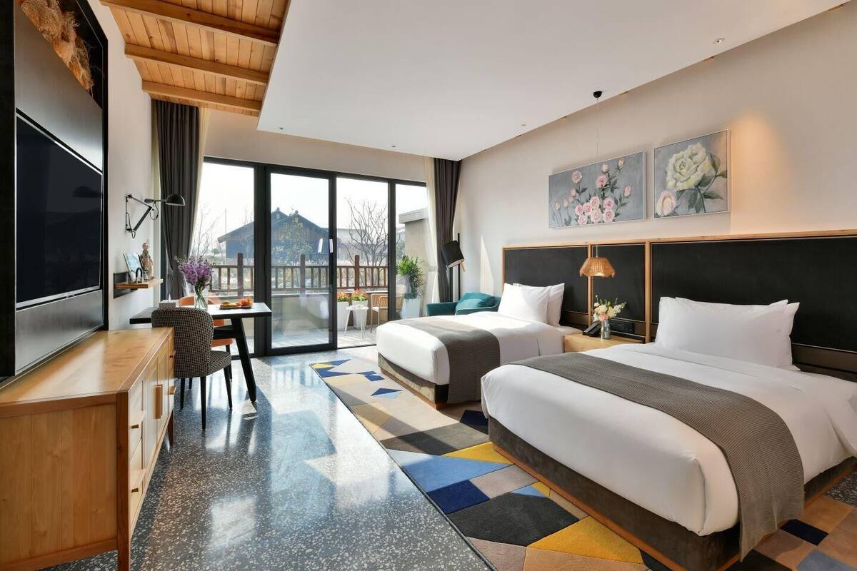 Ein modernes Hotelzimmer mit einem großen Bett, einem Schreibtisch und einem Balkon mit Blick.