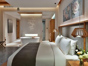 Una habitación de hotel moderna con una cama grande, una bañera y un cabecero de madera.