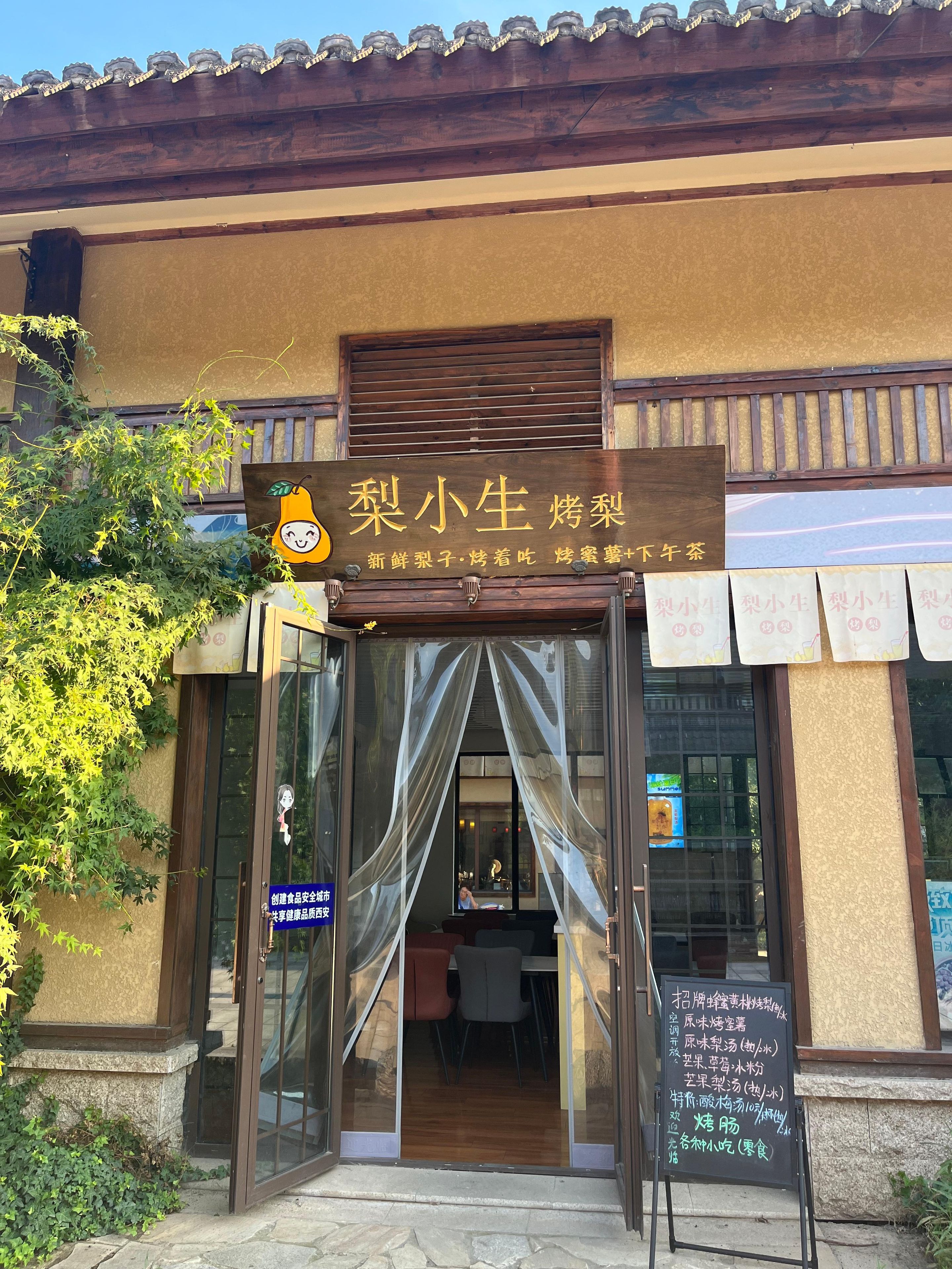 Ein Restaurantzugang mit einem Schild, Glastüren und Blick ins Innere.