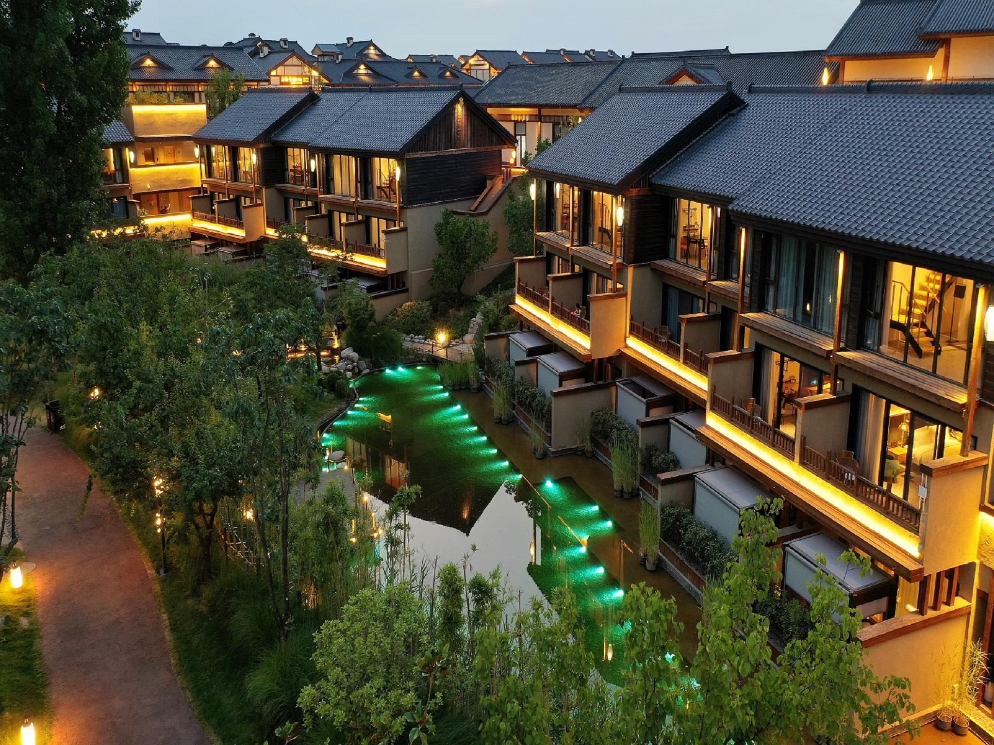 A traditional Japanese-style hotel with multiple connected buildings, a central waterway, and well-lit pathways.