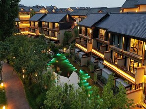 Un hotel tradicional japonés con varias edificaciones conectadas, un canal central y senderos bien iluminados.