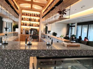 A bar area with a granite countertop, wine bottles on shelves, and a coffee machine. - Blossom Hill Hotel Xian Shijingli (Xi'an)