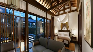 A modern hotel room with a large sofa, a dining table, and a bed with a unique headboard. - Blossom Hill Hotel Xian Shijingli (Xi'an)