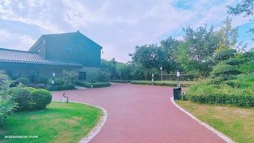 A pathway leading to a building with a traditional architectural style, surrounded by well-maintained greenery.