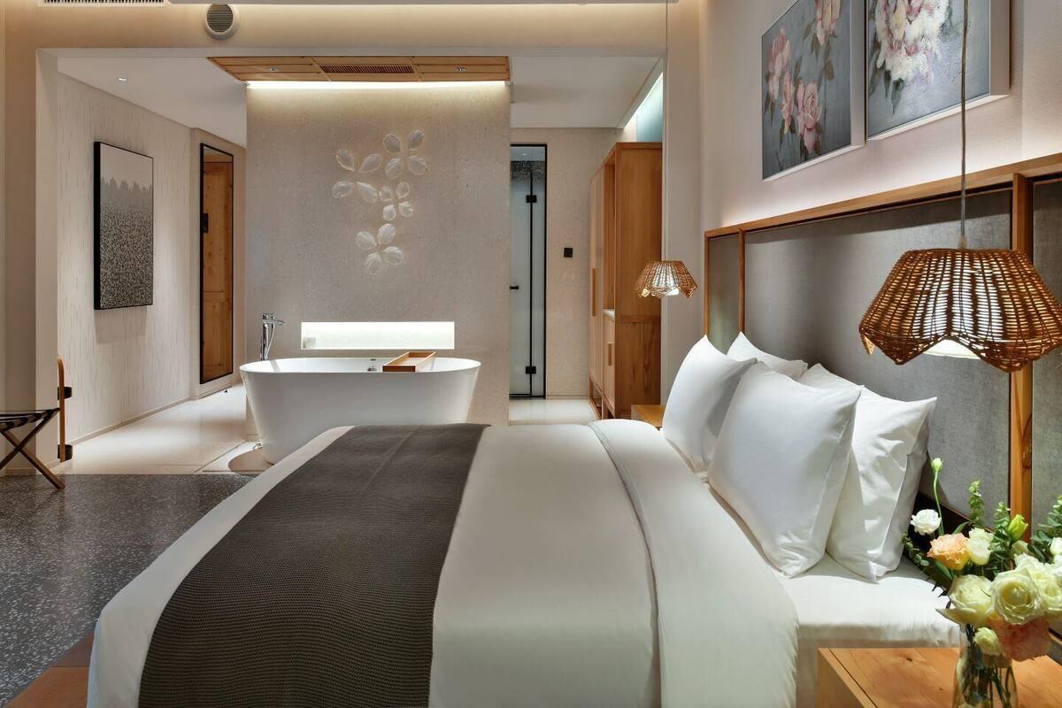 Ein modernes Hotelzimmer mit einem großen Bett, einer Badewanne und einem hölzernen Kopfteil.