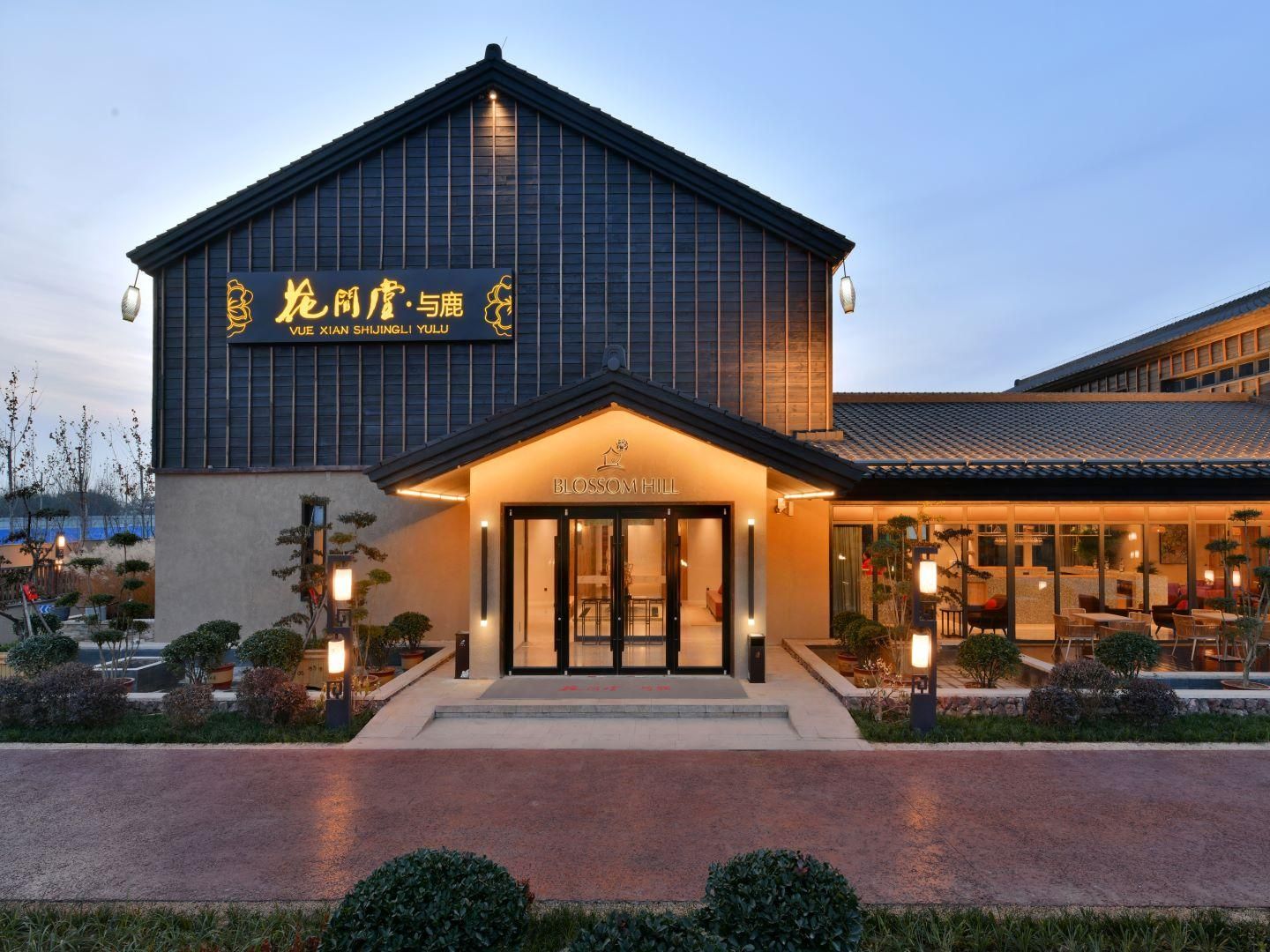 A modern hotel with a large entrance, a sign in a foreign language, and a well-lit exterior.