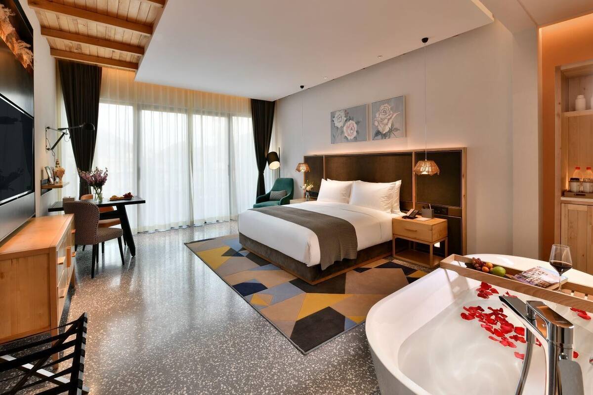 Ein modernes Hotelzimmer mit einem großen Bett, einem Schreibtisch, einem Fernseher und einem Badezimmer mit einer Badewanne.