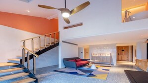 Un interior moderno con una escalera, un sofá y un ventilador de techo.
