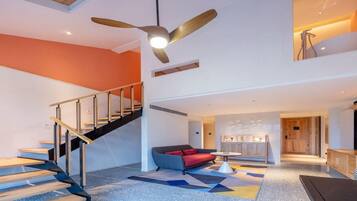A modern interior with a staircase, a sofa, and a ceiling fan.