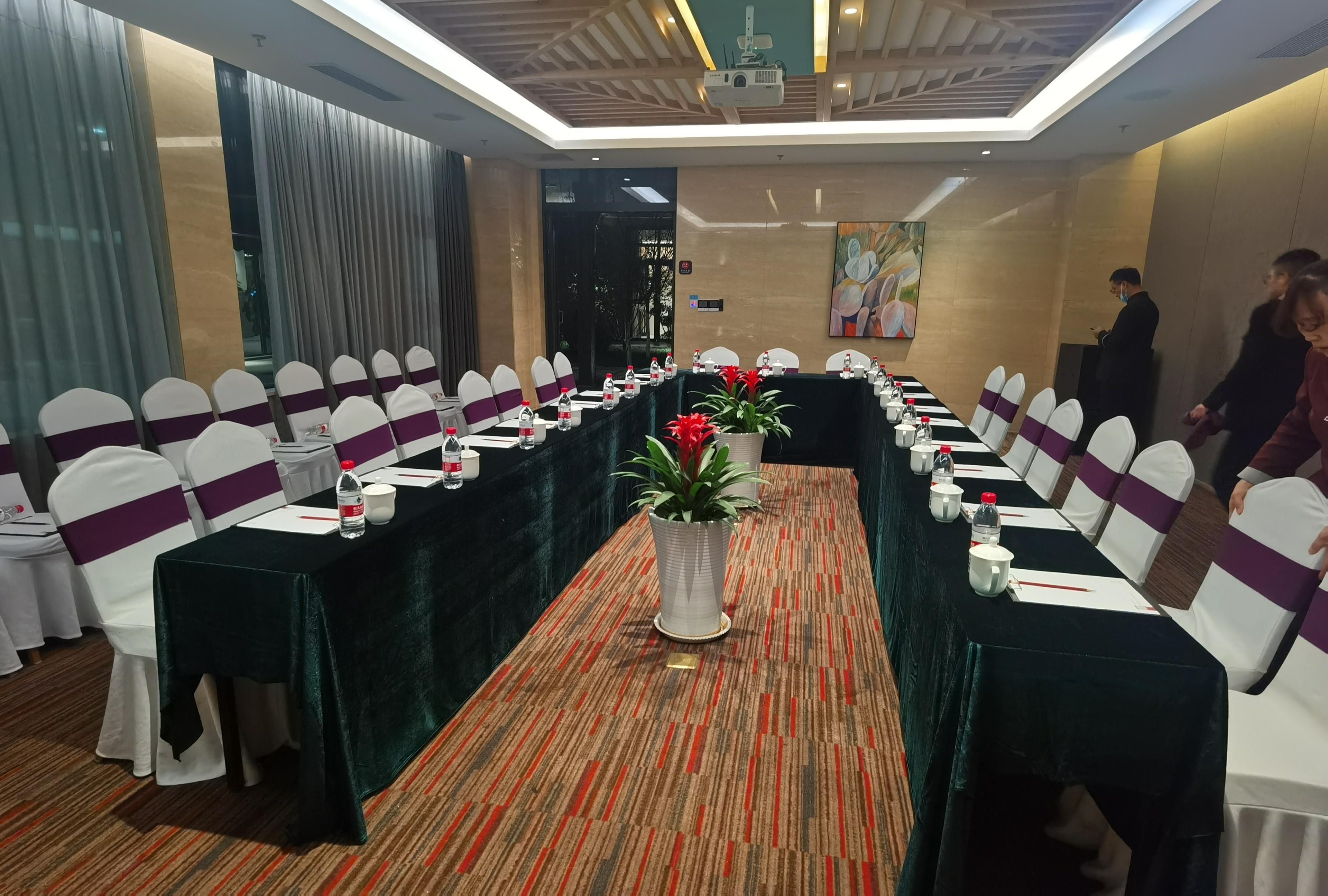 A conference room with a long table, white chairs with purple sashes, and a carpeted floor.