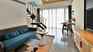 Una sala de estar moderna con un sofá, un comedor, una escalera y un televisor.
