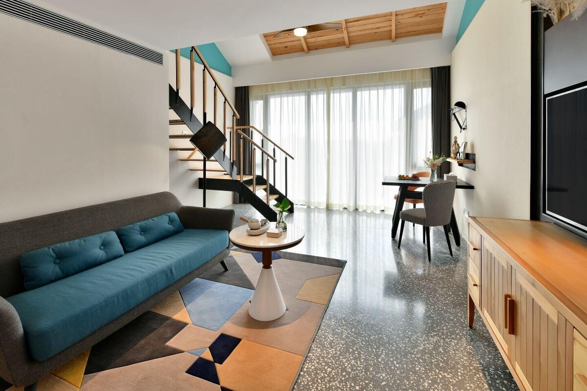 Una sala de estar moderna con un sofá, un comedor, una escalera y un televisor.