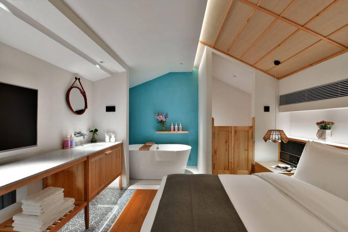 Ein modernes Schlafzimmer mit einem großen Bett, einer eingebauten Badewanne und einer Holzeinrichtung.