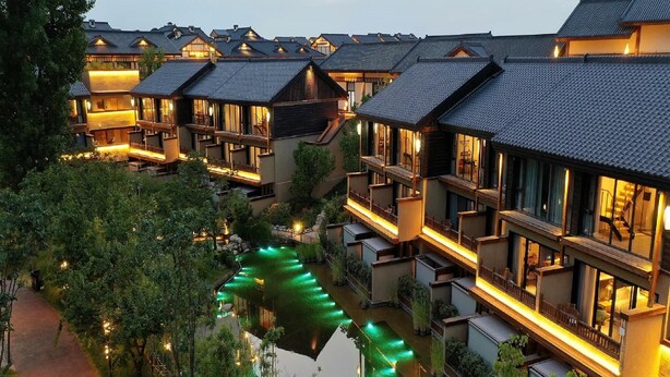 A traditional Japanese-style hotel with multiple connected buildings, a central waterway, and well-lit pathways. - Blossom Hill Hotel Xian Shijingli (Xi'an)