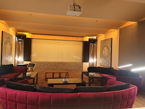 Un salon moderne avec un canapé rouge aux lignes courbes, une petite table en bois et un écran de projection.