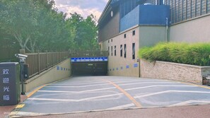 Einfahrt zu einer Parkgarage mit blauem Schild, Überwachungskamera und Ziegelwand.