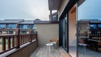 A balcony with a wooden railing, a small round table, and two wicker chairs.
