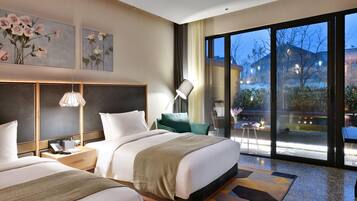 A modern hotel room with two beds, a large window, and artwork on the wall.