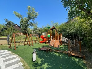 Une aire de jeux avec des balançoires, des toboggans et une structure d’escalade.