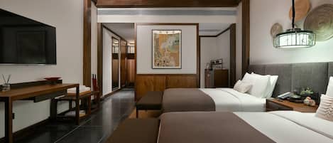 A hotel room with two beds, a wooden desk, a flat-screen TV, and a painting on the wall.