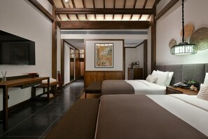 Habitación de hotel con dos camas, un escritorio de madera, un televisor de pantalla plana y un cuadro en la pared.