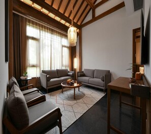 Ein modernes Wohnzimmer mit einer Couch, Sesseln, einem Couchtisch und einem Fernseher.