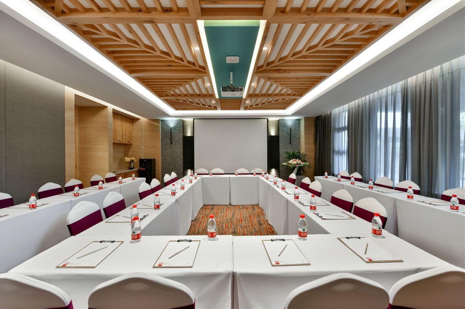 A conference room with a long table, white chairs, and a wooden ceiling.