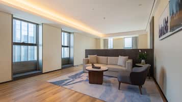 Una sala de estar moderna con sofá, sillón, mesa de centro y un ventanal que proporciona luz natural.