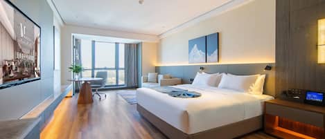 Habitación de hotel moderna con una cama grande, mesitas de noche, un escritorio y vista a la ciudad.