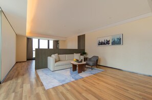 A modern living room with a sofa, armchair, coffee table, and a painting on the wall. - Madison Hotel Qingdao West Coast City Balcony (Qingdao)