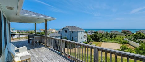 A wooden deck with a view of the ocean and houses.