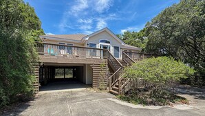 A two-story house with a covered garage entrance, a wooden staircase, and a fenced yard.