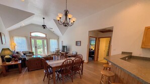 A spacious kitchen with a dining area, wooden furniture, and a large window.