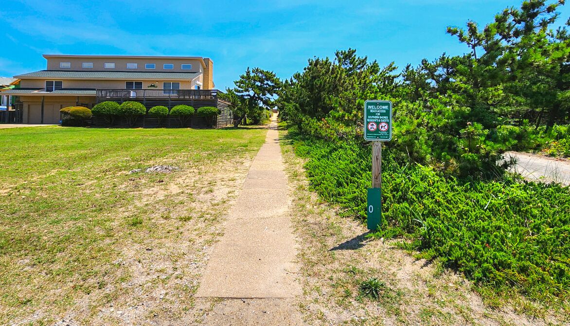 A pathway leading to a building with a welcome sign, surrounded by greenery.