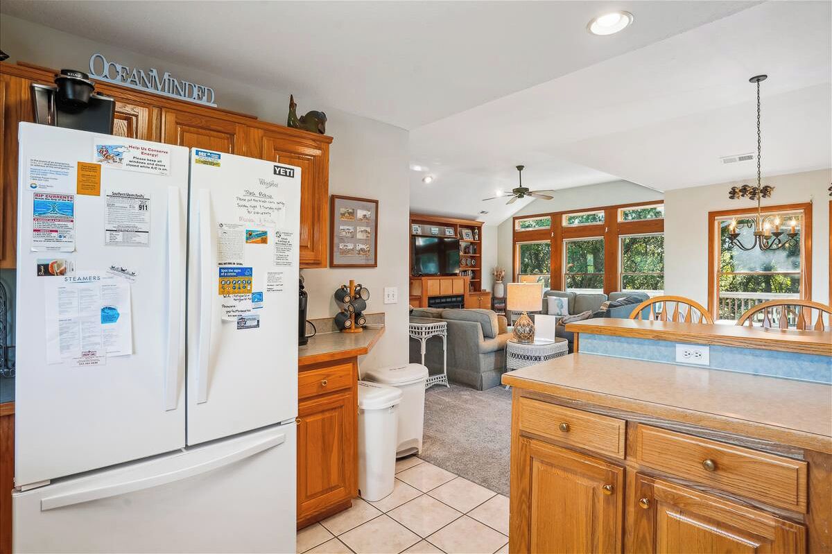 A kitchen with wooden cabinets, a refrigerator, and a dining area with a table and chairs.