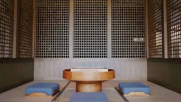 Una habitación tradicional japonesa con esteras de tatami, una mesa de madera central y cojines azules bajos.