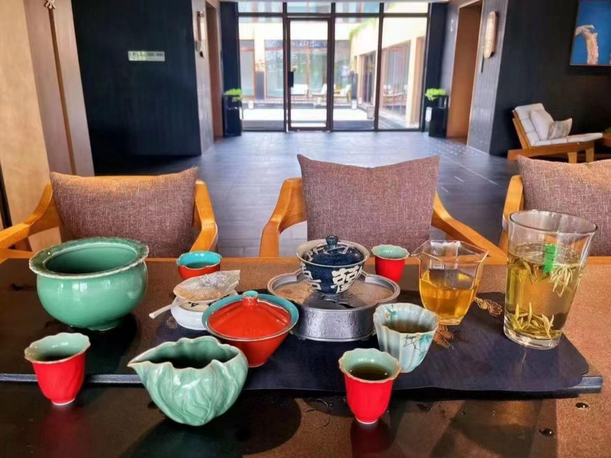 A dining area with a table set for two, featuring various ceramic dishes and a glass of tea.