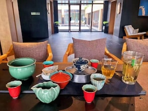 A dining area with a table set for two, featuring various ceramic dishes and a glass of tea. - Blossom Hill Hotel Nanjing Lishui (Nanjing)
