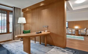 A hotel room with a wooden desk, a green chair, a lamp, and a vase with flowers. - Blossom Hill Hotel Nanjing Lishui (Nanjing)