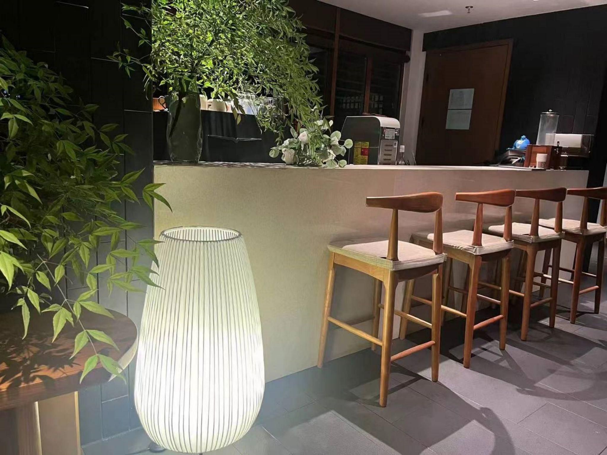 Zona de bar con sillas de madera y una lámpara grande con textura.