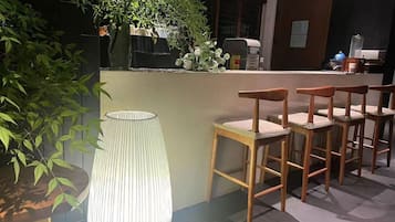 Zona de bar con sillas de madera y una lámpara grande con textura.