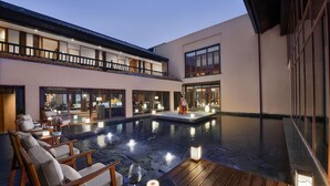 Un hotel moderno con piscina en la azotea, zona de estar al aire libre y un interior bien iluminado.