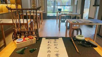 A traditional Japanese room with tatami flooring, a low table with a tea set, and a wooden chair.