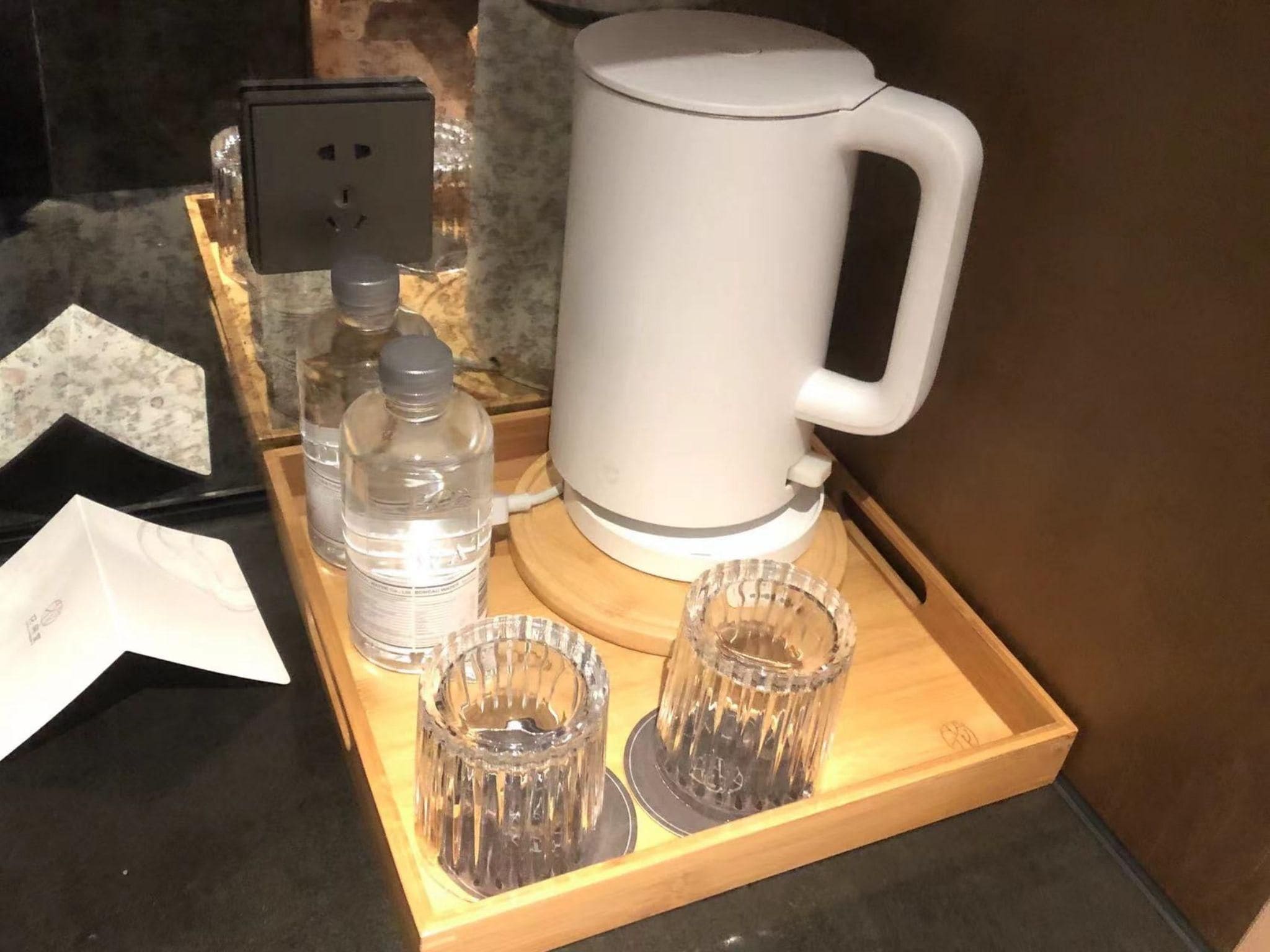 A coffee maker, a water bottle, and two glasses on a tray.