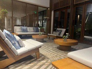 A modern lounge area with a sofa, armchairs, and a coffee table, featuring a patterned floor and wooden partitions. - Blossom Hill Hotel Nanjing Lishui (Nanjing)