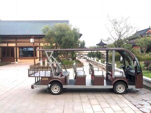 A traditional rickshaw with a passenger seat and a cargo area, parked on a paved area with a building and trees in the background. - Blossom Hill Hotel Nanjing Lishui (Nanjing)