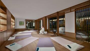 A yoga studio with wooden floors, mats, and a person practicing.